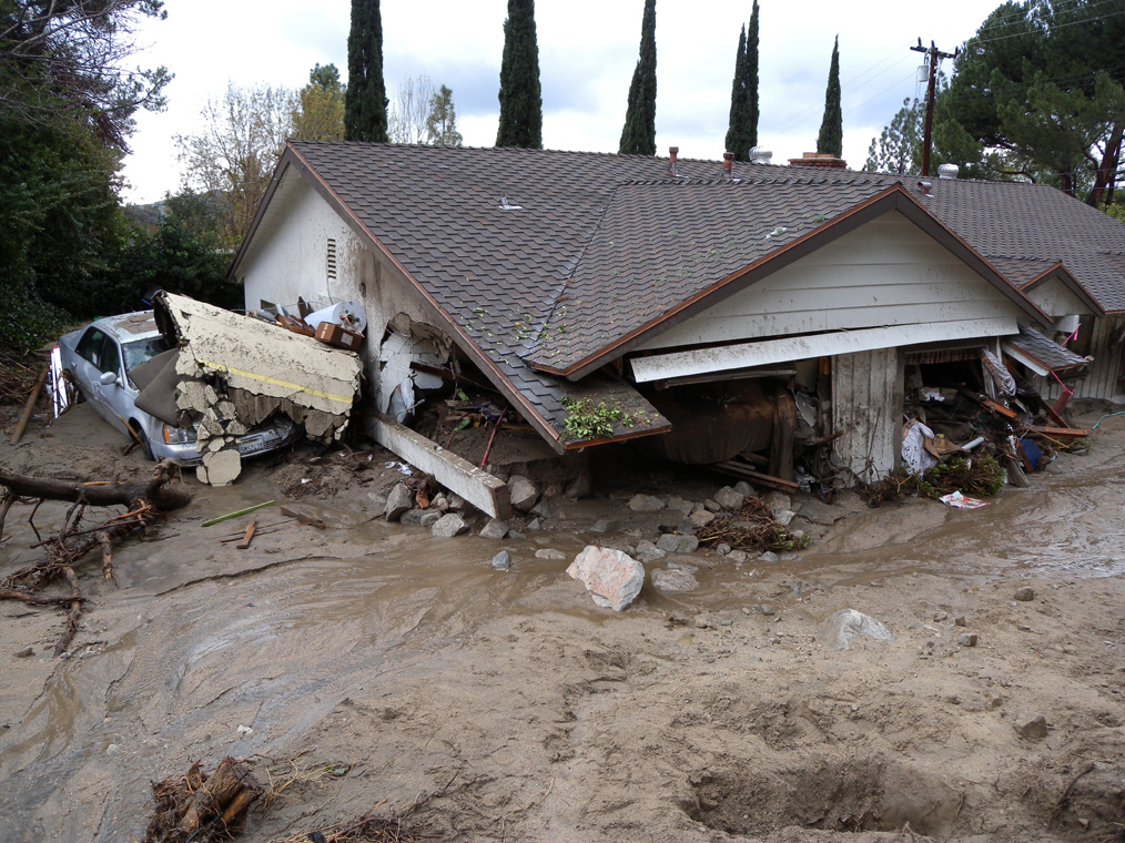 A mudflow that broke through a containment basin in February 2010, destroyed a this home north of Los Angeles, California, and filled it with boulders, mud, and tree stumps.  Credit: USGS 
