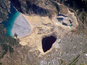 A satellite view of Berkeley Pit and Yankee Doodle tailings pond in Butte, Montana. The pool is the former site of a massive copper mine and is just one remnant of Butte’s extensive mining history. Credit: NASA.  
