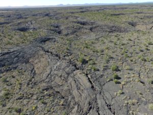 An aerial view of the McCartys flow field in western New Mexico, which is twice the size of Washington, D.C. Cracks in the rock show how the lava shrank as it cooled. Inflation pits can also be seen: pits that formed when the lava flowed and inflated around an obstacle. Credit: Christopher Hamilton. 