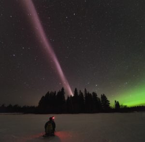 Alberta Aurora Chasers capture STEVE on the evening of April 10, 2018 in Prince George, British Columbia, Canada. Robert Downie kneels in the foreground while photographer Ryan Sault captures the narrow ribbon of white-purple hues overhead. The vibrant green aurora is seen in the distant north, located to the right in the photo. Credit: Ryan Sault.
