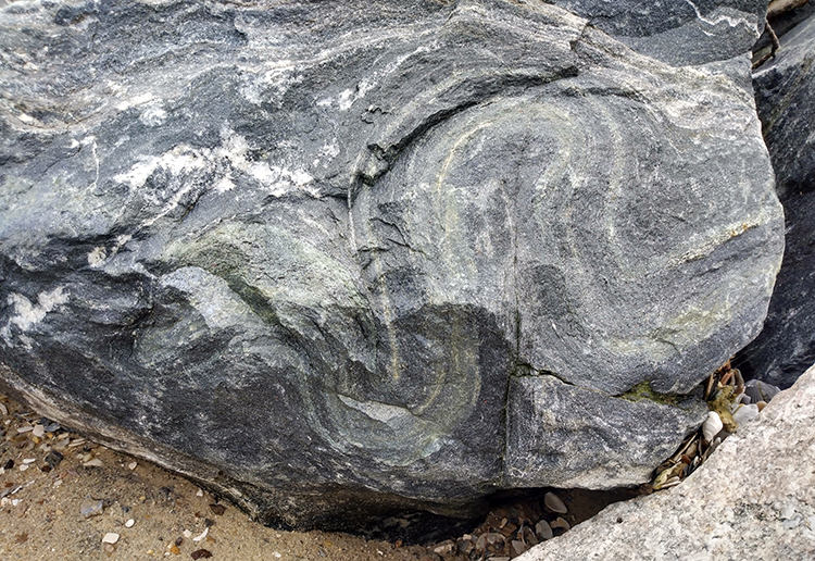 Folded epidote layer in a boulder of ripr