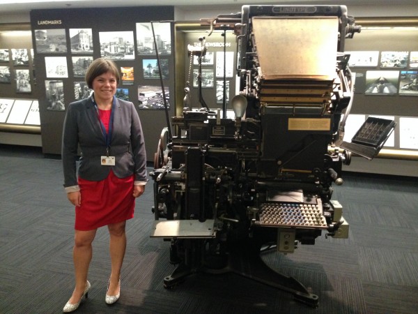 Julia Rosen, AGU’s 2014 Mass Media Fellow, who has a Ph.D. in paleoclimatology, stands next to an old newspaper production machine at the Los Angeles Times, where she spent the summer working as a science reporter. Photo by Dione Rossiter, AAAS.