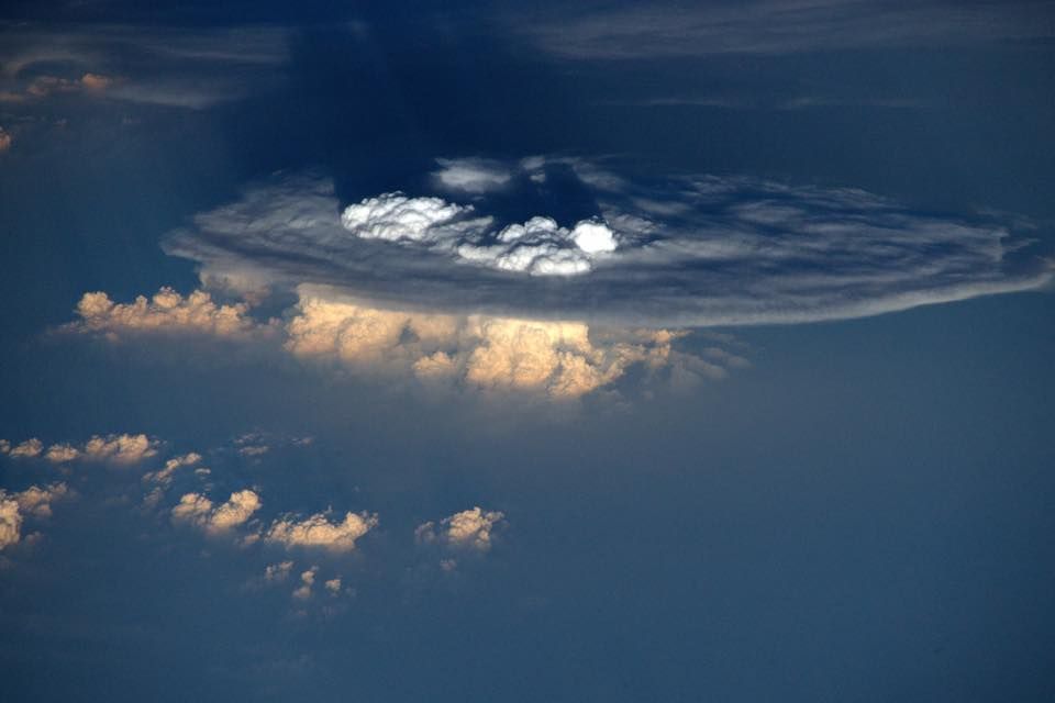 Anvil clouds as seen from the ISS. Clouds form when humid rising air condenses water vapor into water droplets; anvil clouds form at the tropopause, the boundary between the troposphere and stratosphere, as higher temperatures in the stratosphere prevent further rising. Overshooting tops, as seen in the middle of this anvil cloud, occur when particularly strong convection causes air to overshoot the tropopause and briefly enter the stratosphere before sinking back into the troposphere.